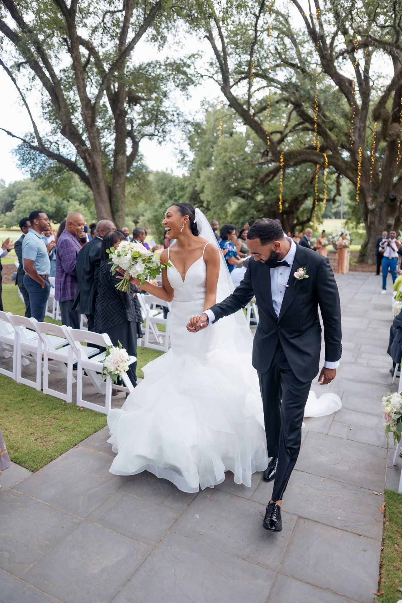 Joyful newlyweds walking back down the aisle after their outdoor ceremony