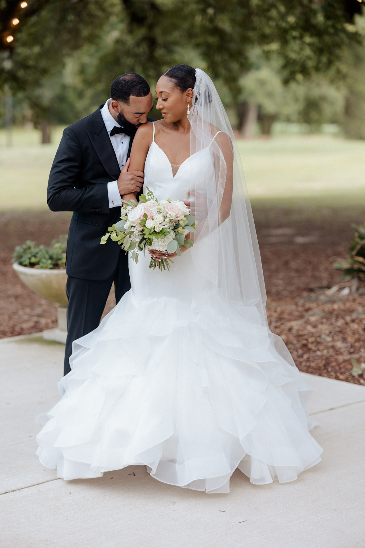 Newlyweds embracing beneath the trees